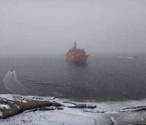A ship sits on a line with supporting vessels in the snow
