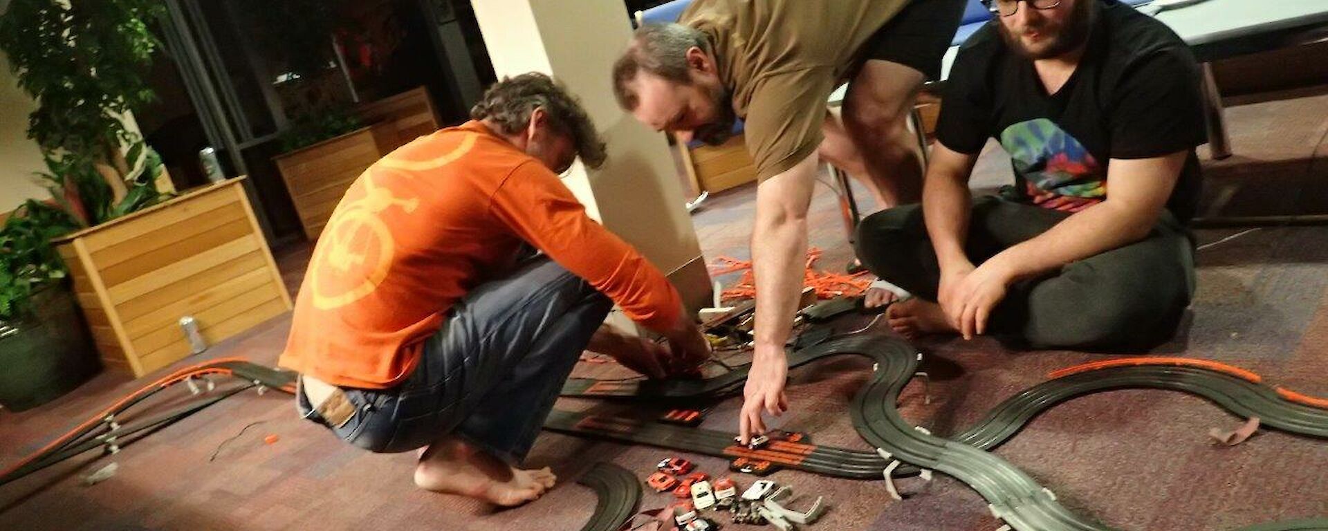 3 men playing with a slot car system