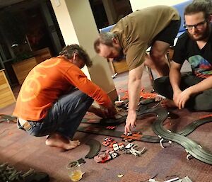 3 men playing with a slot car system