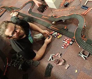 A man smiles for camera in front of a slot car track