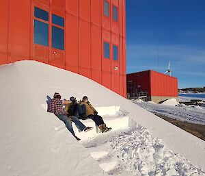 3 people sit on a step cut into a snow bank