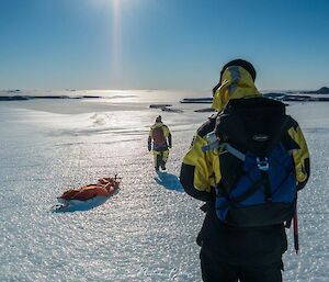 a man hauls a sled while another looks on