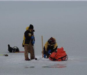 2 men out on the sea ice with some equipment