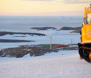 The sun sets on the horizon with Mawson station in foreground