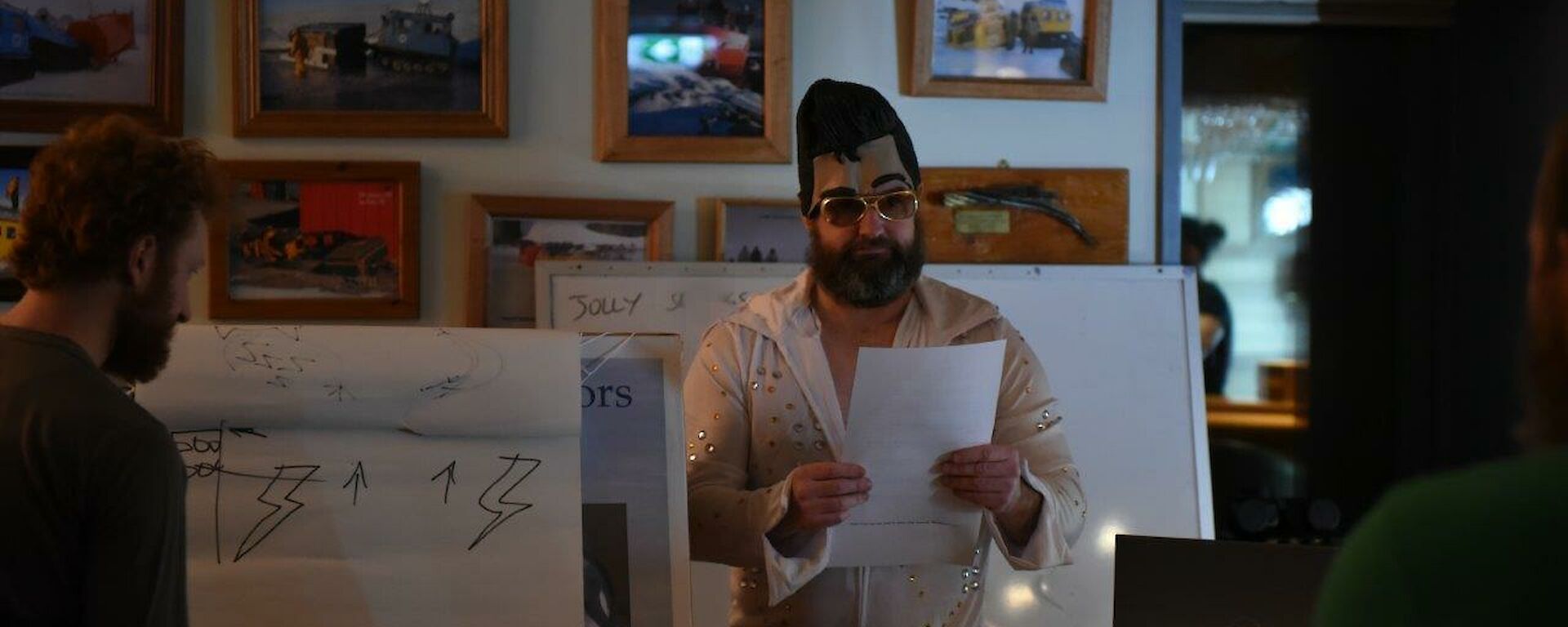 A man dressed as Elvis watches a man drawing
