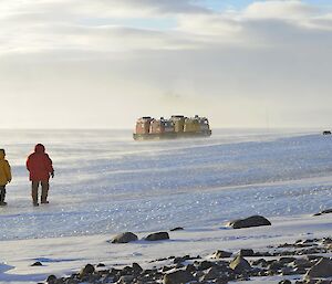 2 men walk towards 2 Häggs on the ice plateau