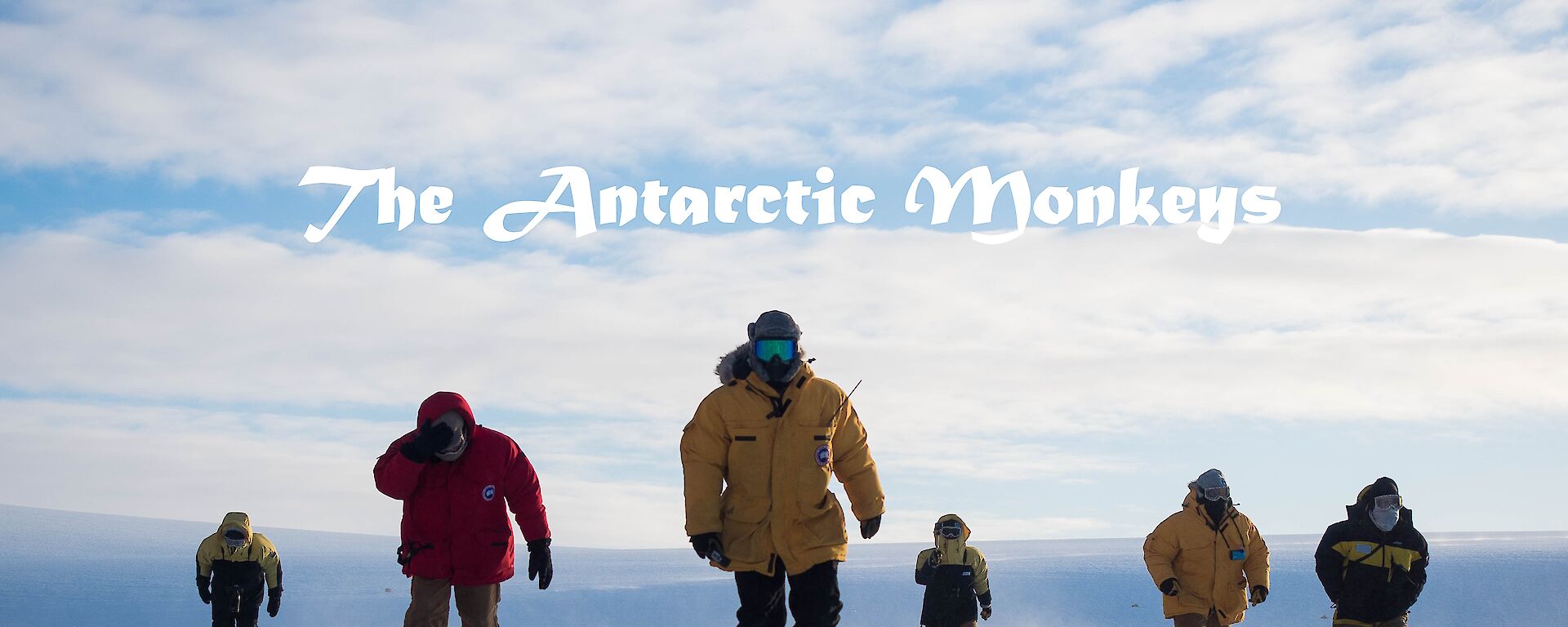 Six men walk towards camera across the ice