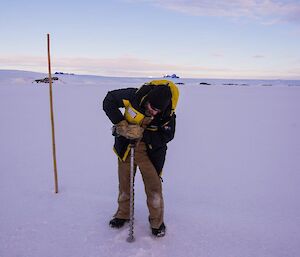 A man drills a hole in the sea ice
