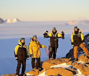 4 men stand on a rocky surface with the ice plateau behind