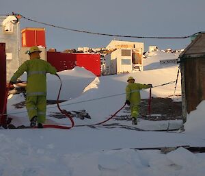 2 men readying the fire hoses for the exercise