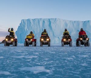 5 poeple on quad bikes in front of an iceberg