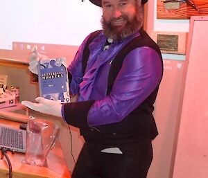 A man in fancy dress holds up a quiz book