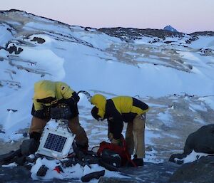 2 men changing camera cards at one of the penguin cameras