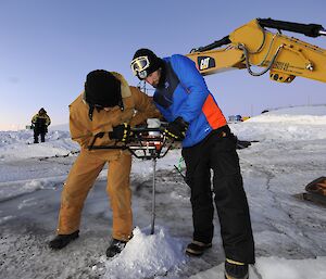 2 men drilling a hole in the sea ice