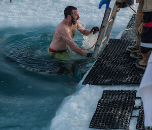 A man coming out of the swimming hole