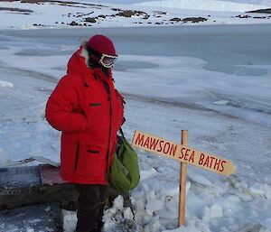 A woman stands by the swimming hole in full winter clothing