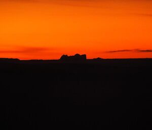 A bright orange sky with iceberg in foreground