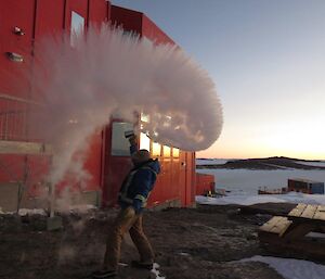 A man throws boiling water in the air to make a cloud