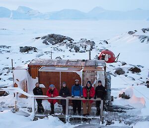 A group of people pose ont he balcony of Macey hut