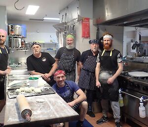 A group of men stand in the kitchen