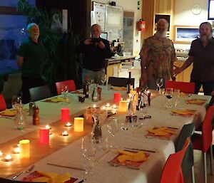 A group of men stand next to a set dinner table