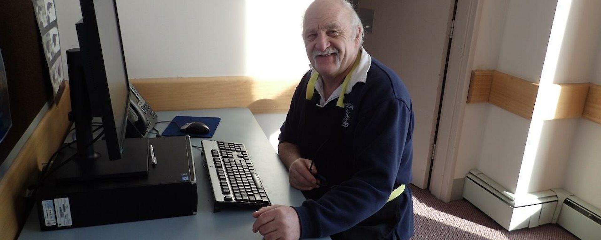 A man smiles while sitting at a desk.