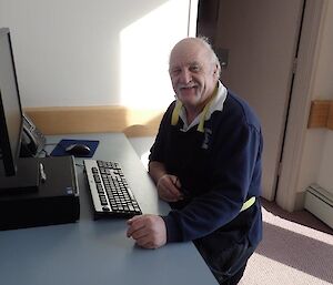 A man smiles while sitting at a desk.