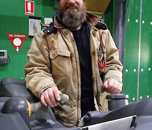 A man smiles at camera from a forklift