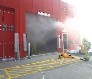 Smoke coming out of building with firefighter in front