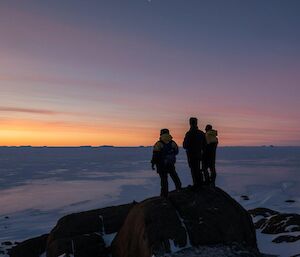 Three men watch the sunset at Macey Island