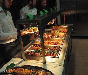 3 men in front of a full buffet