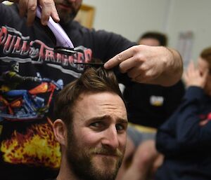 One man cuts another man’s hair