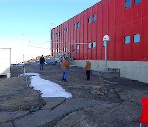 4 people play badminton by the Red Shed