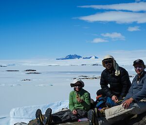 3 people sit on an island in front of an ice view