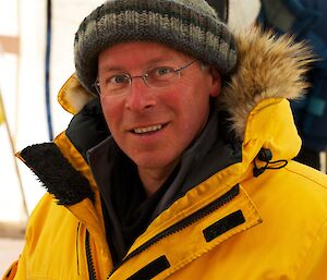 Dr Tas van Ommen in the field wearing a yellow Antarctic Division jacket.
