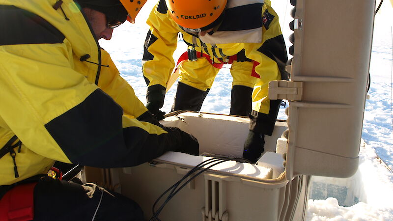 Two scientists prepare to bury the GPS in its protective case, for burial on the Sørsdal Glacier.