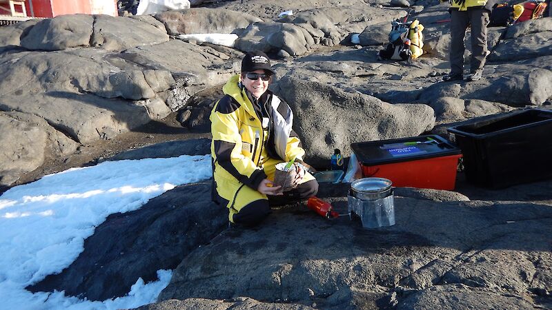 Eleri sitting on a rock cooking pasta on her camp stove.