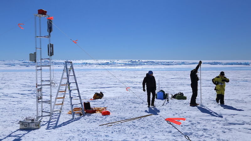 Three expeditioners with the tower being erected on the Sørsdal Glacier.