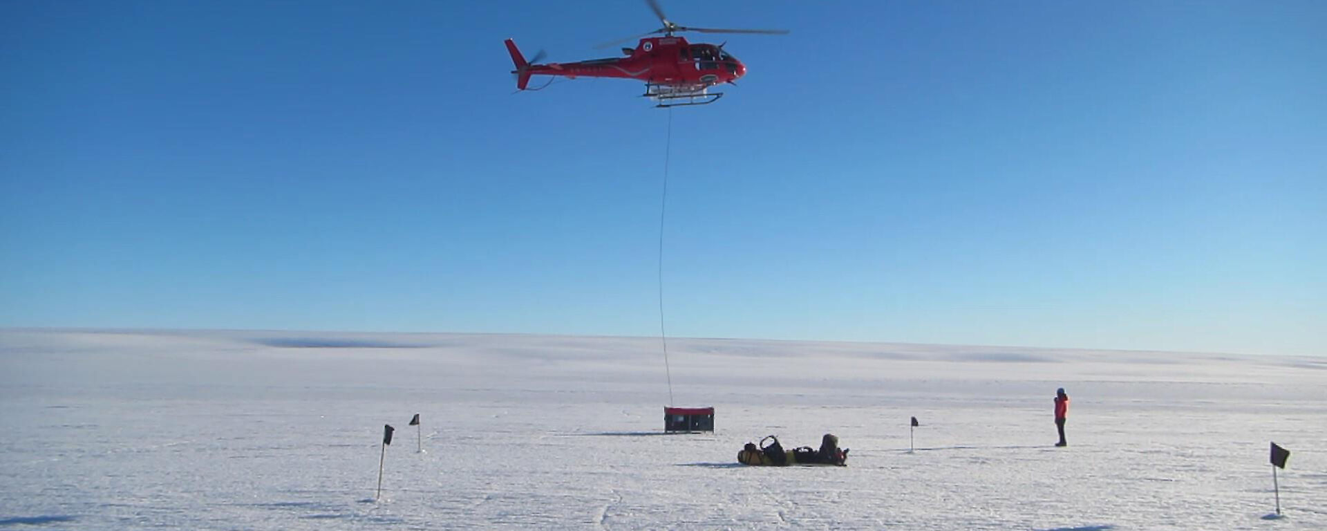 The helicopter gently begins to lift a cage pallet full of equipment to a new site on the glacier.