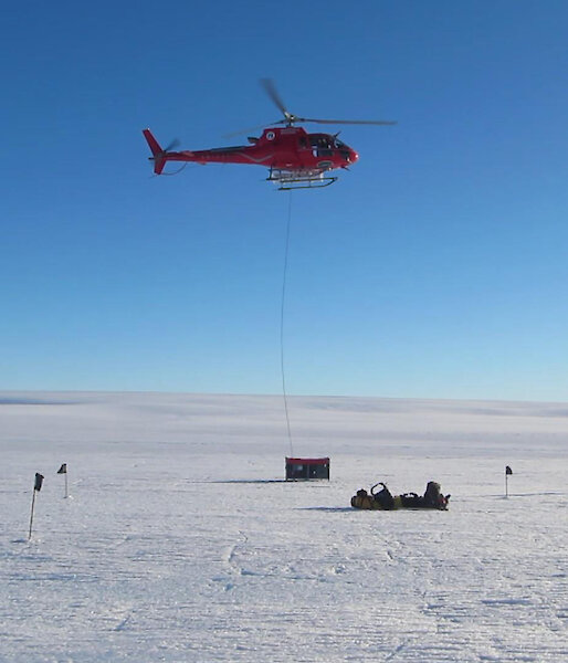 The helicopter gently begins to lift a cage pallet full of equipment to a new site on the glacier.