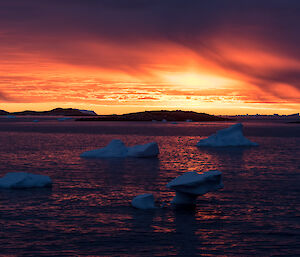 A spectacular red and orange sky at sunset at Davis, with ice bergs in the ocean