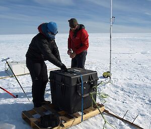 Two expeditioners strap down equipment on the ice