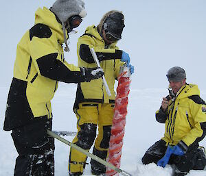 Three scientists collect an ice core in Antarctica.