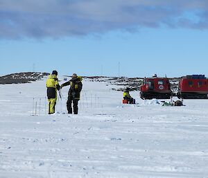 Scientists marking out an area on the ice surface with poles.