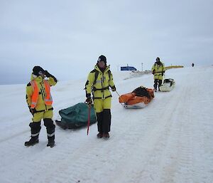 Scientists drag science equipment on sleds across the fast ice.