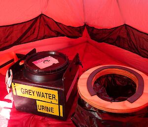 The field toilet — a bucket lined with plastic, and a seat.