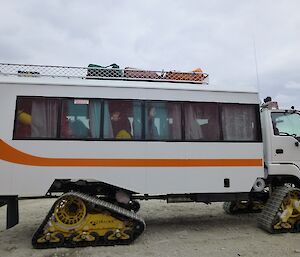 Expeditioners wave goodbye from a tracked bus.