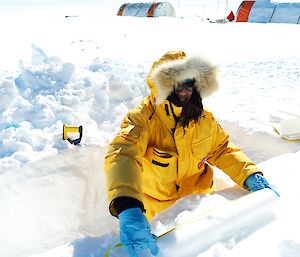 A scientist with an ice core in a drill pit.