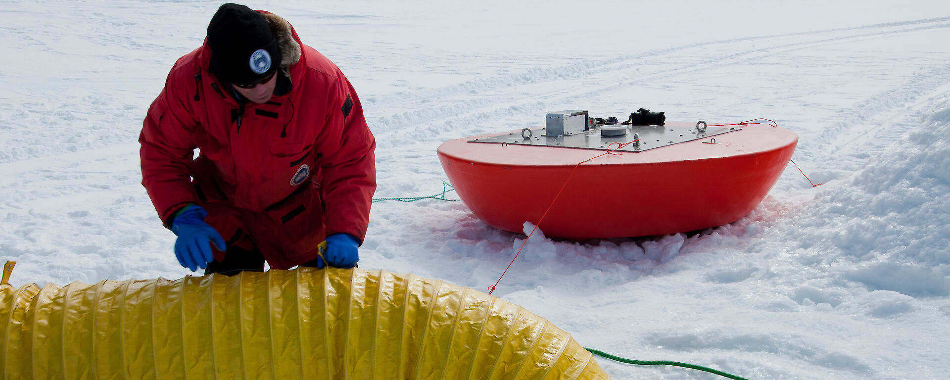 antFOCE project researcher at ice dive hole feeds slinky into the enclosed underwater chamber