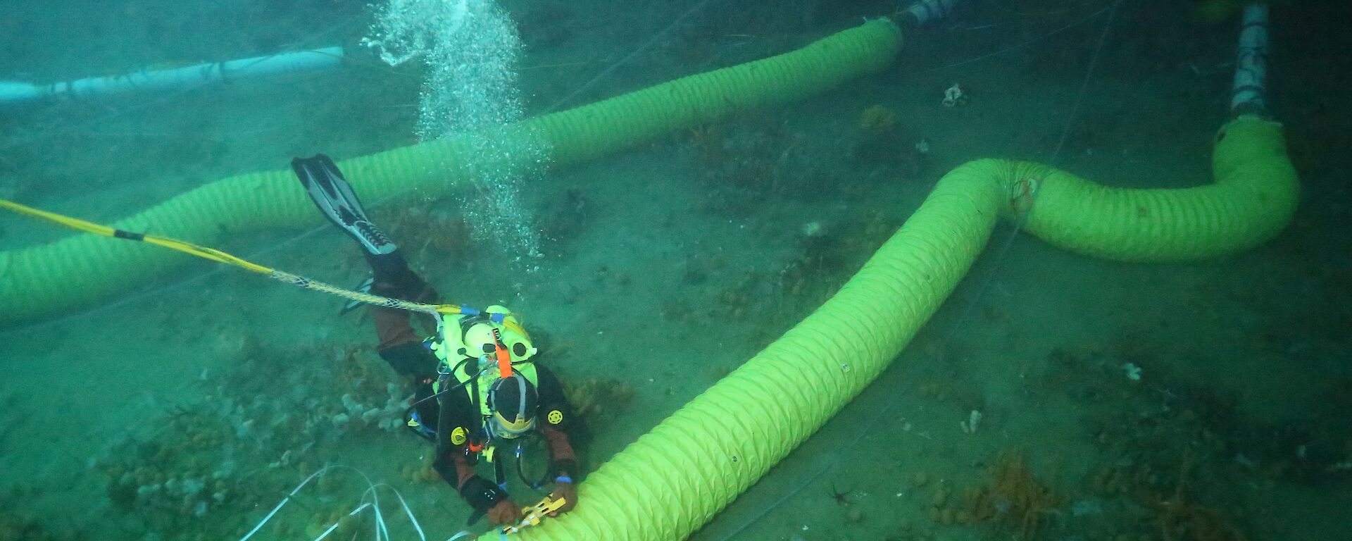 A diver working on a lowered duct. The inlet and the thrusters tubes which draw water into the experiment can be seen in the top right hand corner